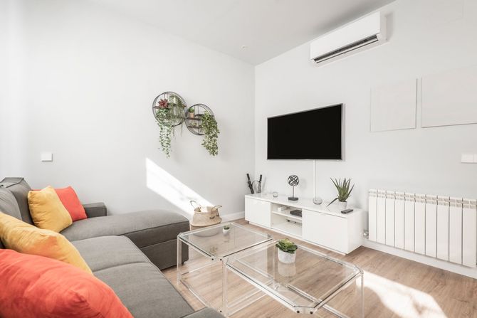 Una sala de estar con sofá, mesa, televisión y aire acondicionado.