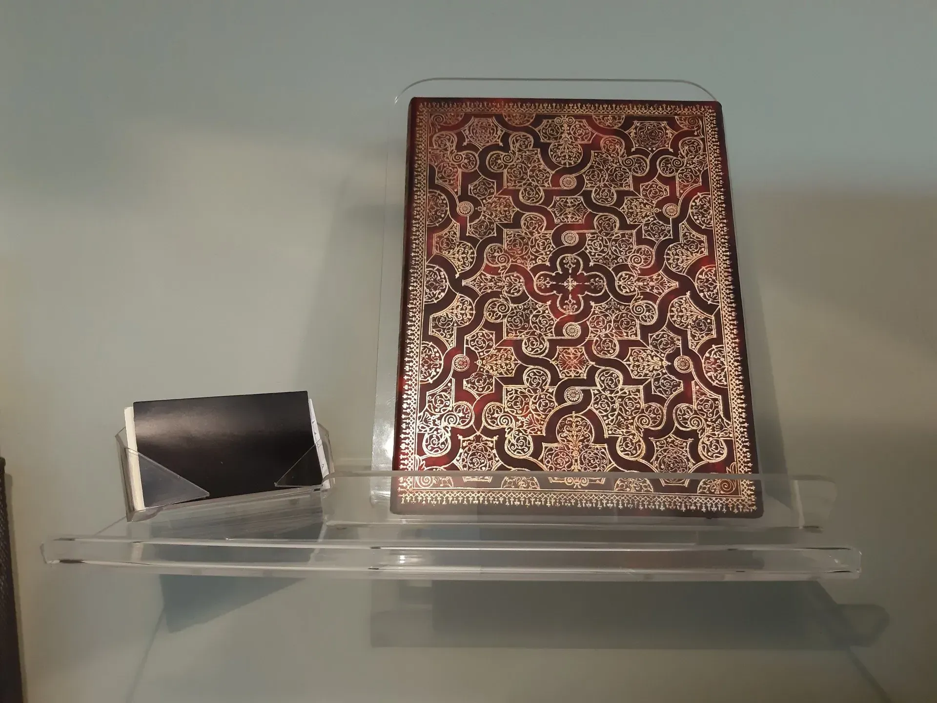 Un libro está en un estante transparente con un patrón.