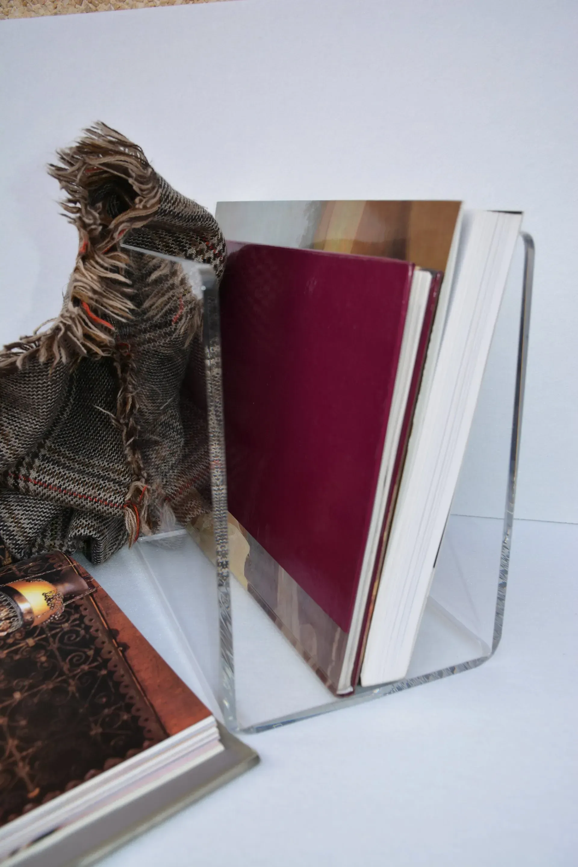 Un soporte transparente para libros sostiene dos libros y una manta.