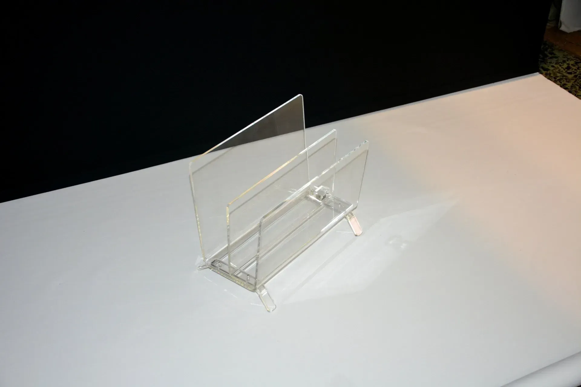 Un porta tarjetas de acrílico transparente se encuentra sobre una mesa blanca.