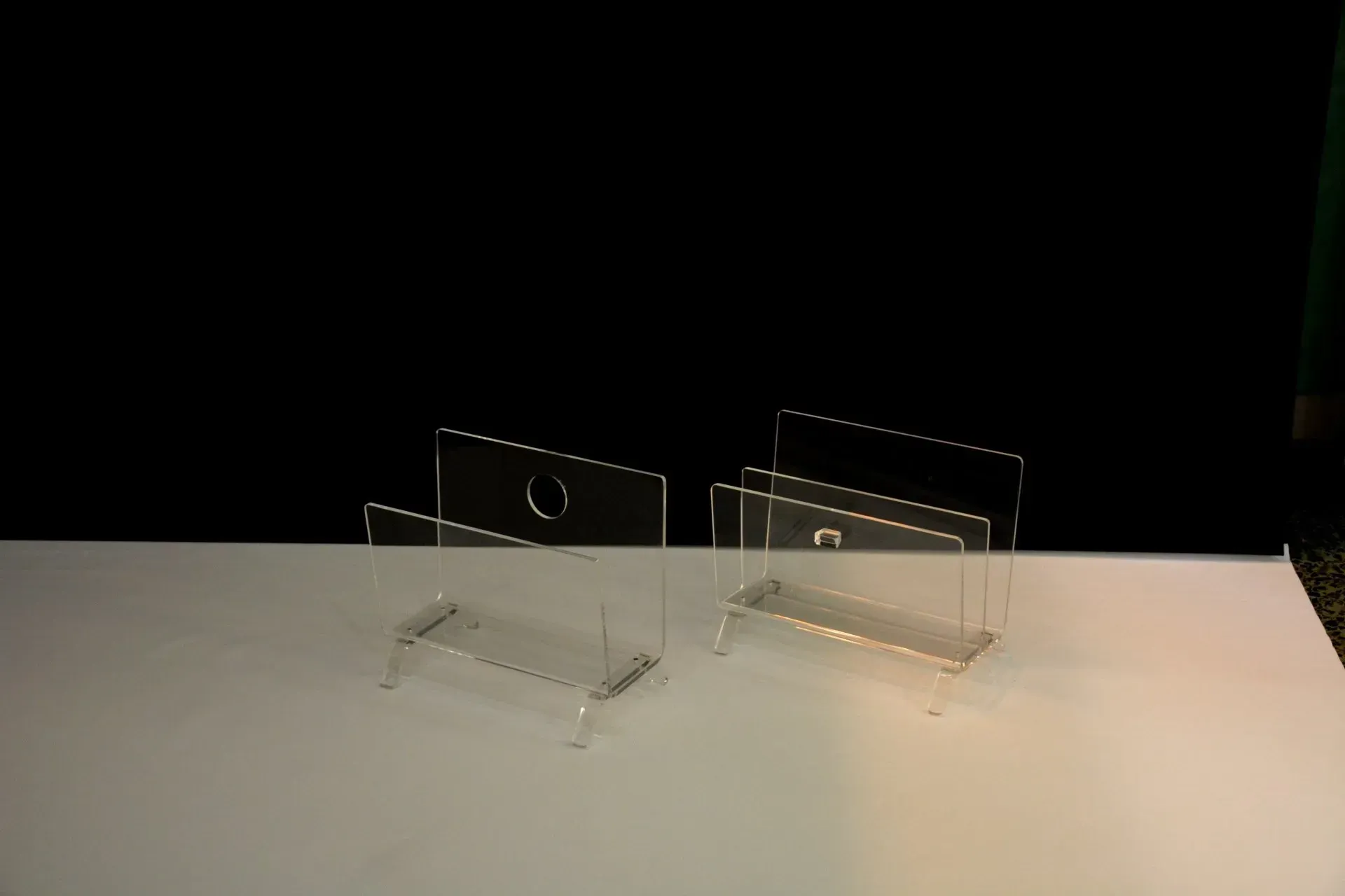 Dos porta tarjetas de acrílico transparente están sobre una mesa blanca.