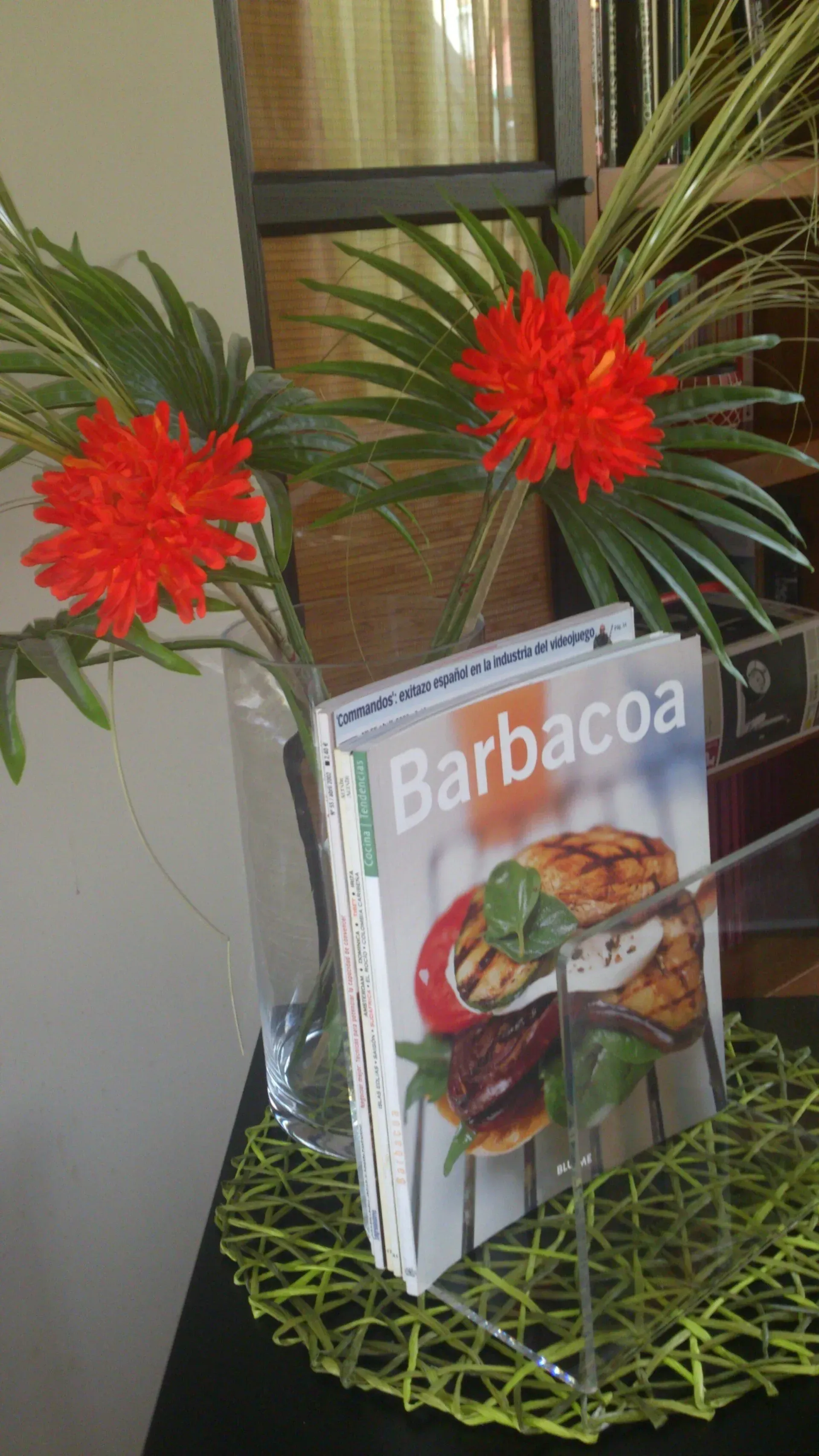 Un libro titulado Barbacoa está sobre una mesa al lado de un jarrón de flores.
