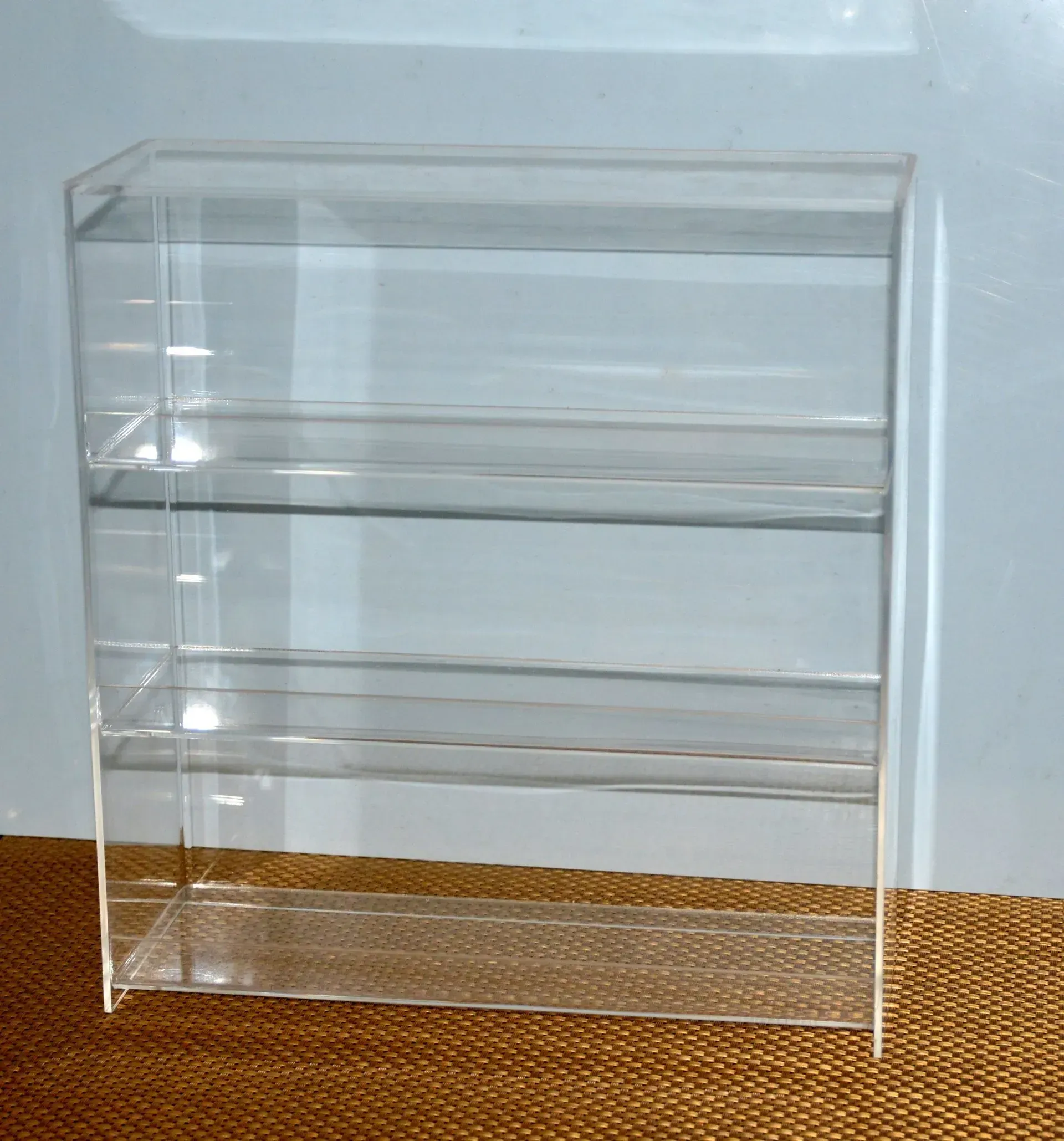 Un estante de acrílico transparente se encuentra sobre una alfombra marrón.