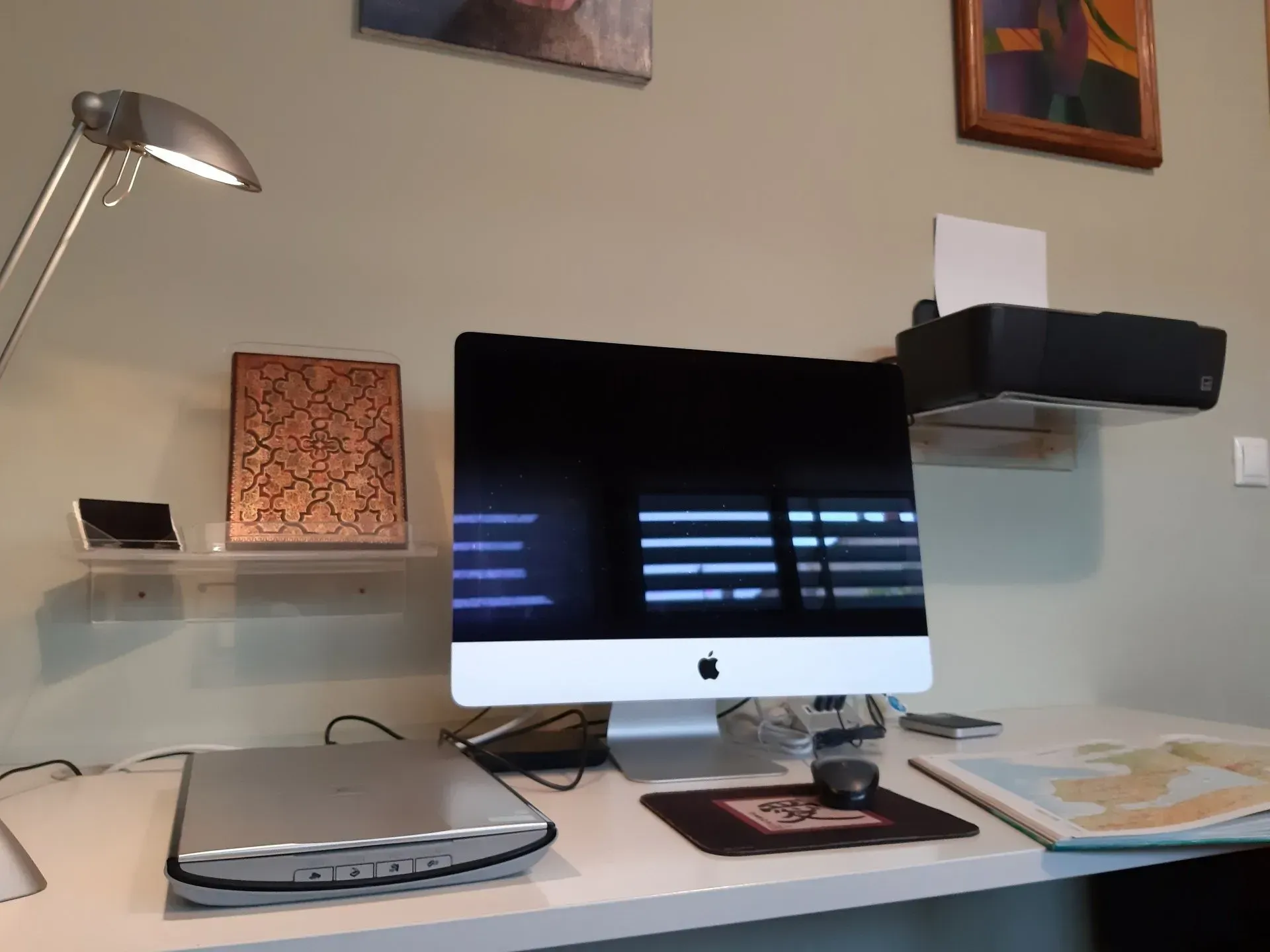 Una computadora Apple se encuentra en un escritorio junto a una impresora.