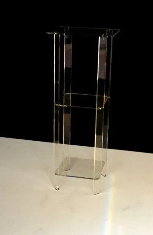 Un podio de acrílico transparente está sobre una mesa blanca.