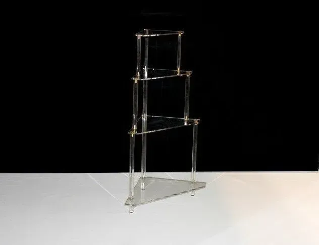 Un estante de acrílico transparente está encima de una mesa blanca.