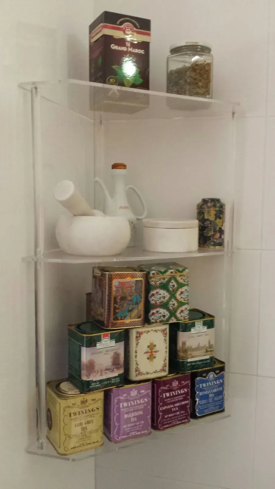 Un estante lleno de cajas de té y un mortero.