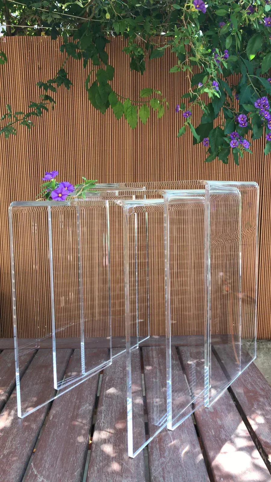Tres mesas de acrílico transparente están colocadas sobre una mesa de madera.