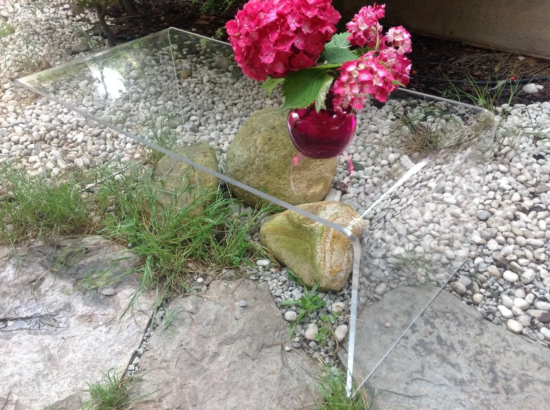 Un jarrón de flores está sobre una mesa de cristal.
