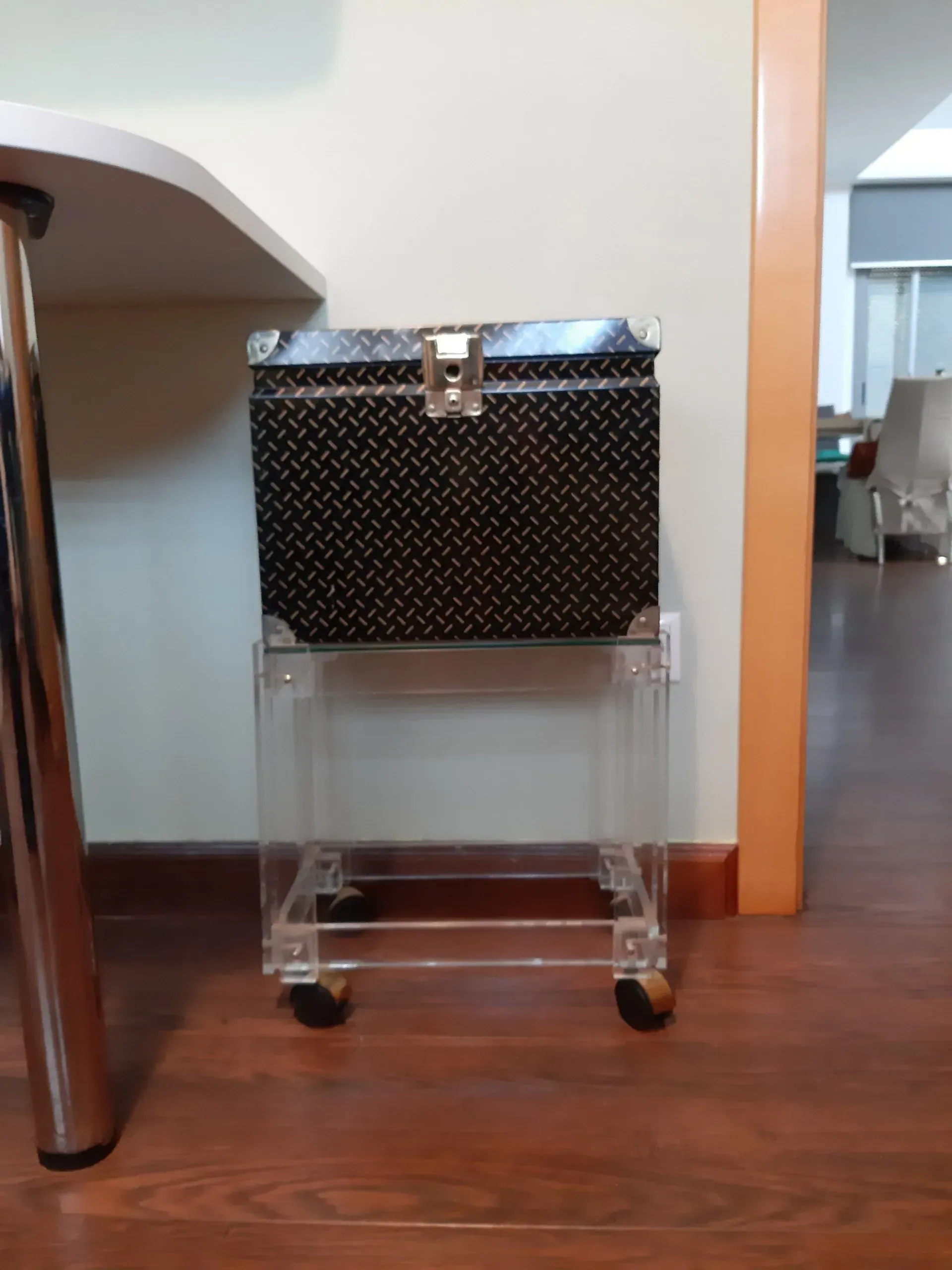 Un pequeño baúl con ruedas se encuentra junto a un escritorio.