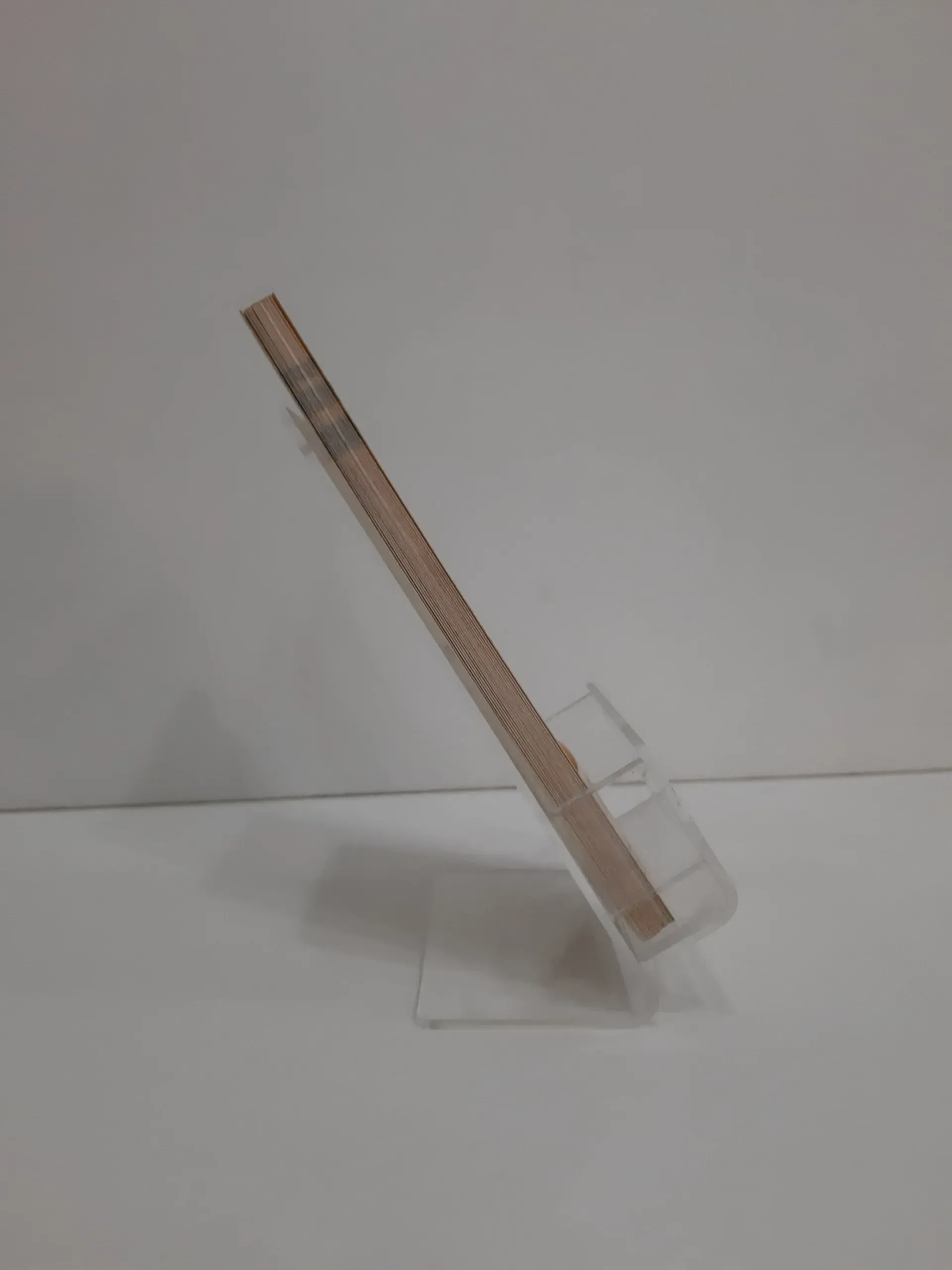 Un teléfono celular está colocado encima de un soporte transparente.