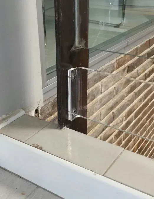 Un primer plano de una puerta de vidrio con una pared de ladrillos al fondo.