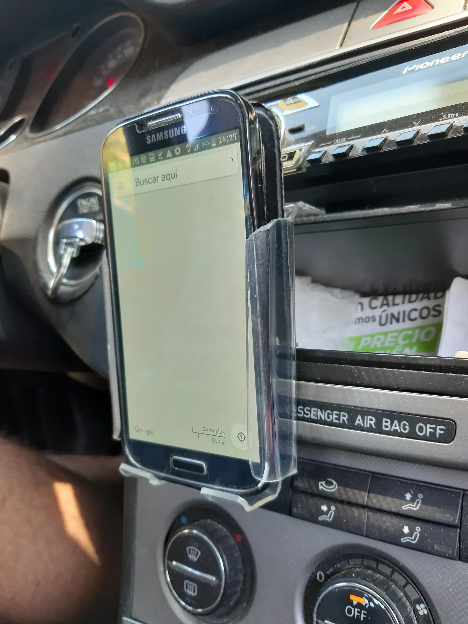 Un teléfono celular está en un soporte transparente en el tablero de un automóvil.