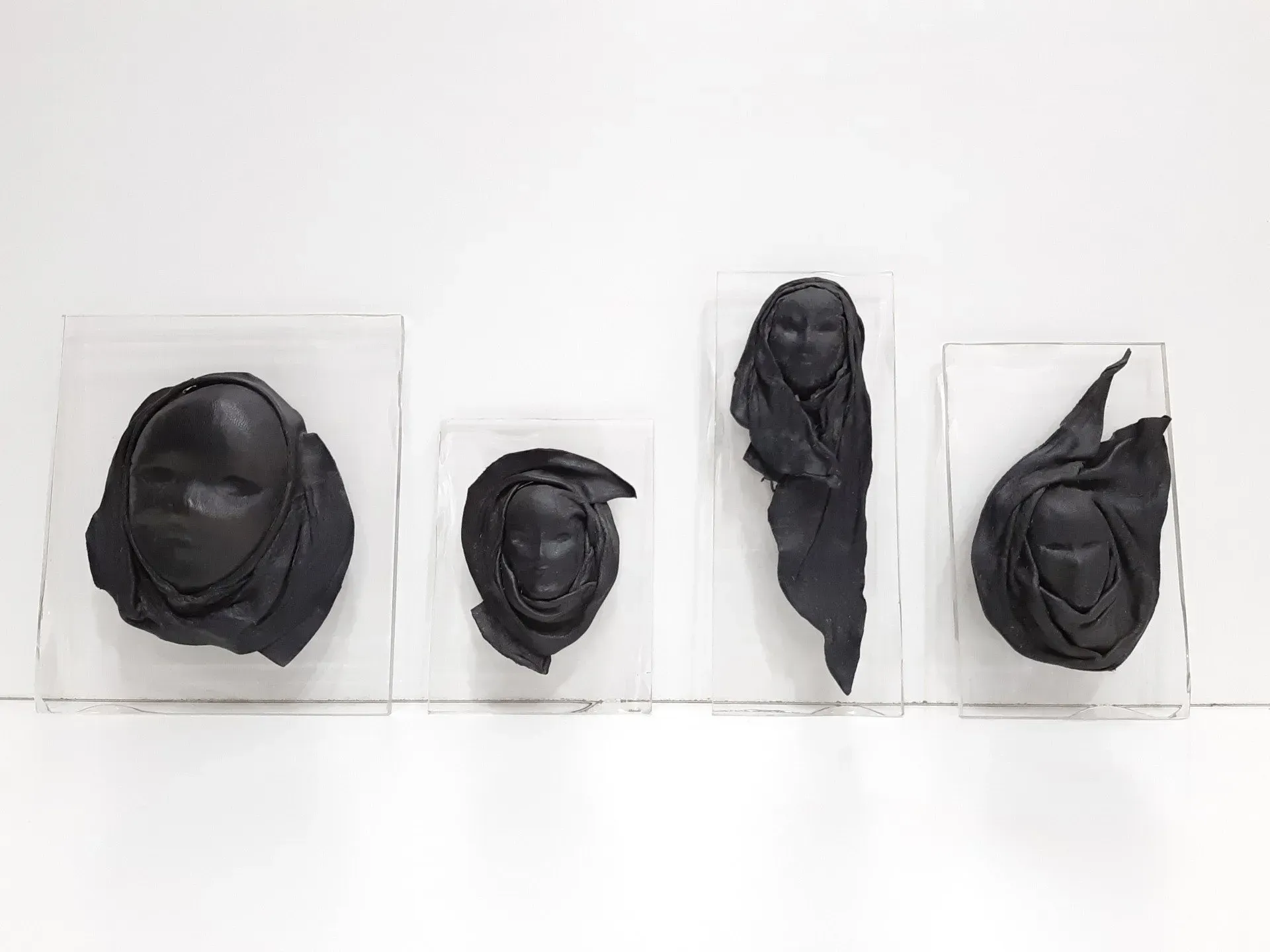 Un grupo de máscaras negras están sentadas una encima de otra sobre una superficie blanca.