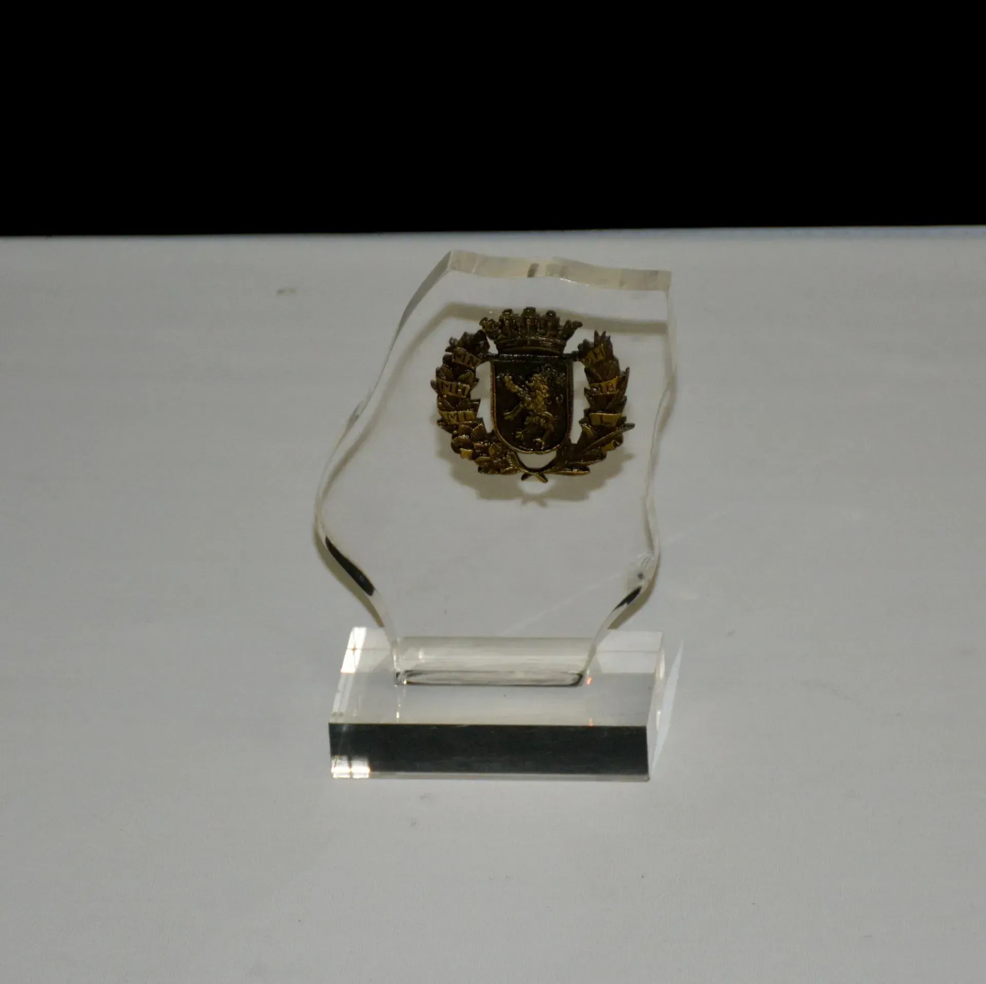 Un trofeo de cristal transparente con un león encima.