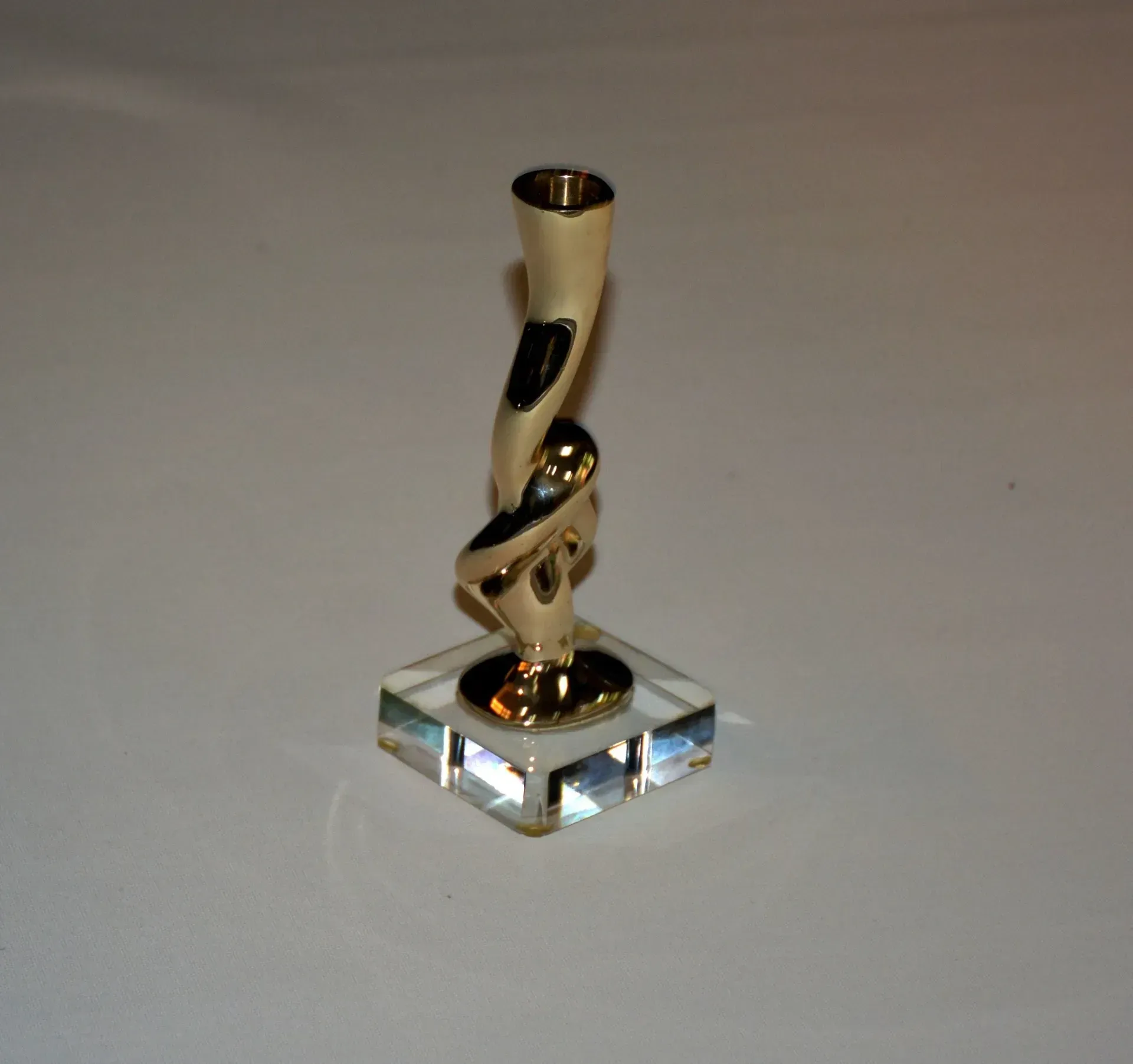 Un pequeño objeto dorado se encuentra sobre una base de vidrio transparente.