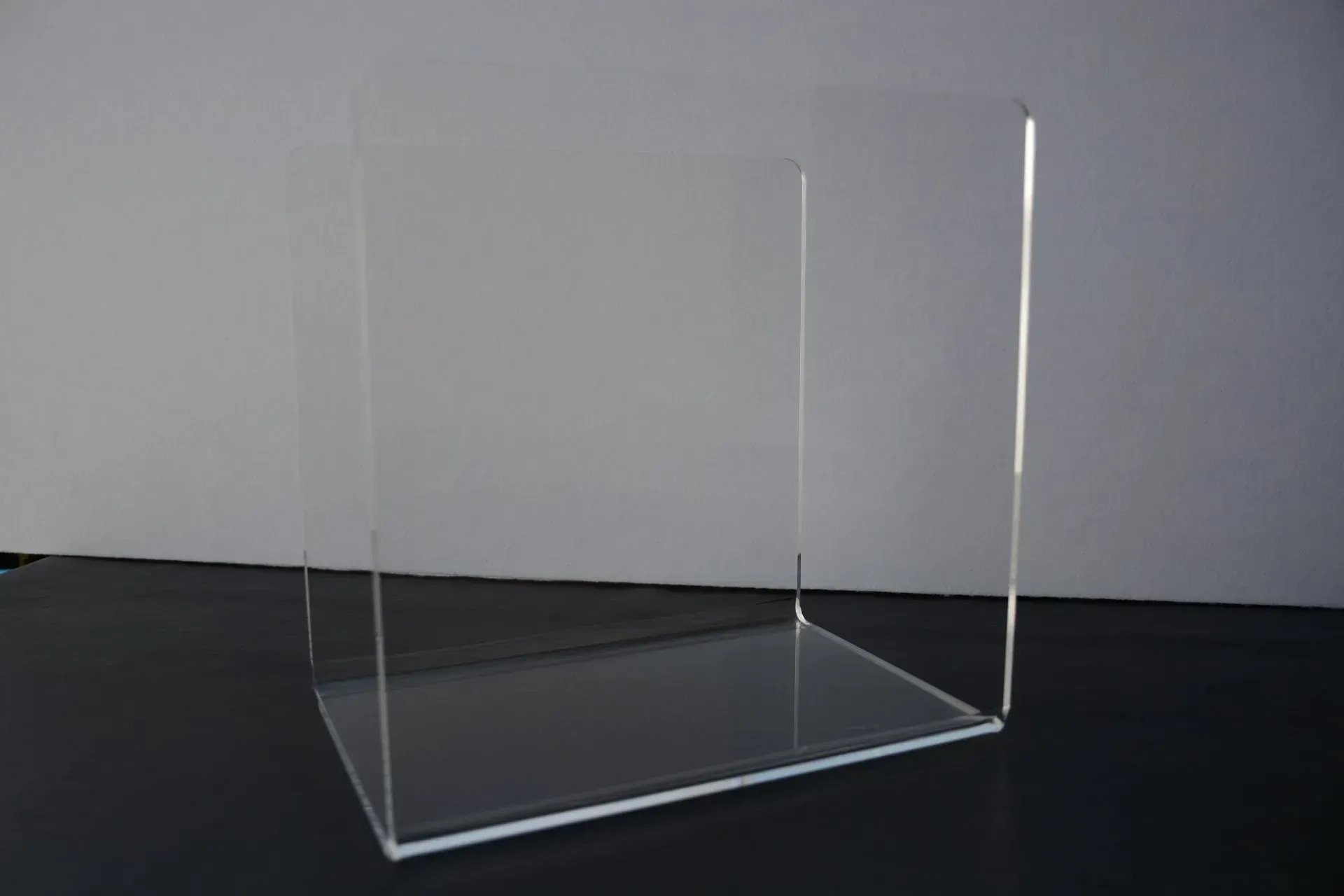 Una caja de acrílico transparente está sobre una mesa negra.