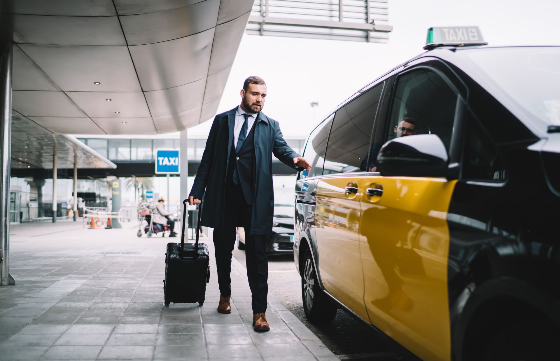Un homme avec des bagages, entrant dans un taxi jaune et noir dans un aéroport.