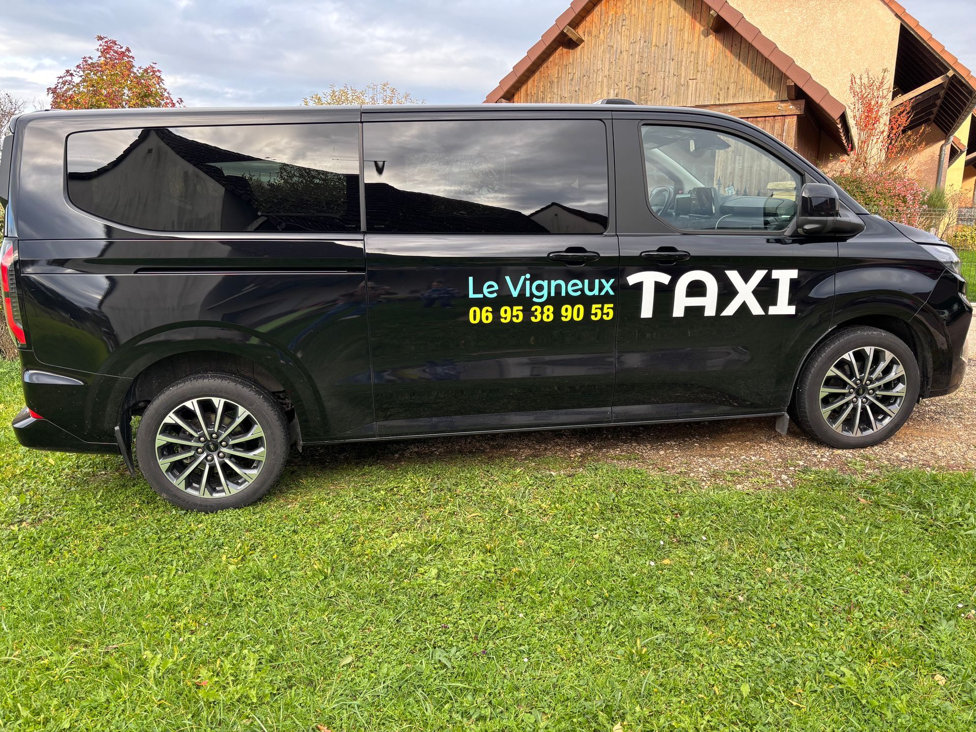 Une personne ouvre une portière de voiture noire. À l'intérieur, une personne est assise à l'arrière. Extérieur, lumière du jour.