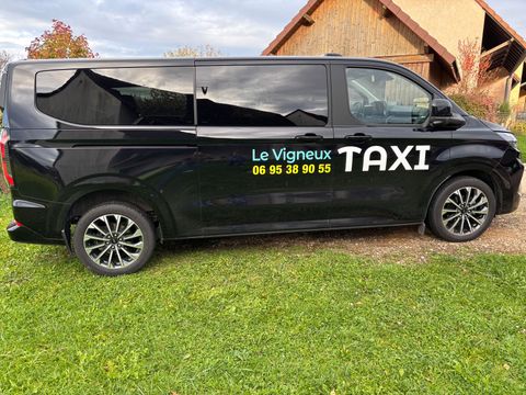 La main d'un homme portant un costume, tendant la main vers la poignée de la portière d'une voiture, à côté d'une voiture noire.