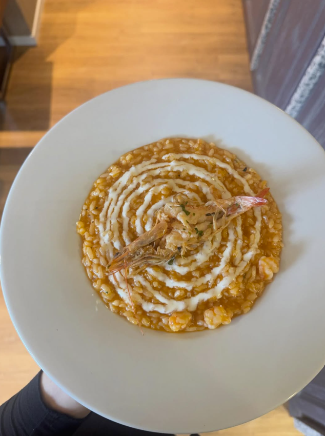 Ein hölzerner Präsentationstisch mit Weinflaschen, Pflanzen und Regalen in einem Raum mit Backsteinwänden.