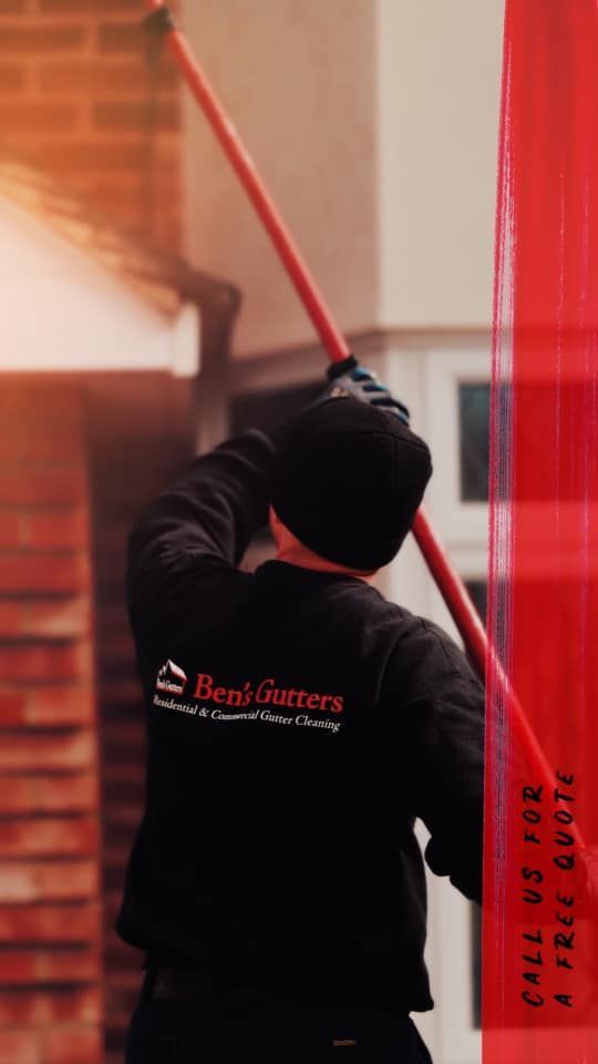 Person in black jacket using a long pole to clean a red wall or window frame indoors