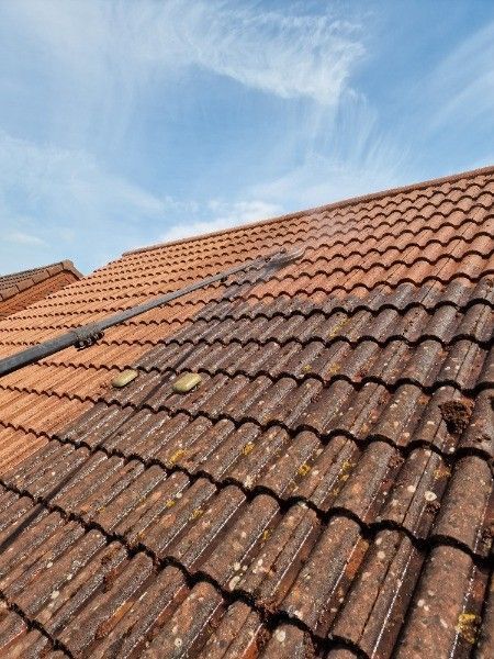 Red tiled roof with dark moss or weather stains under a blue sky