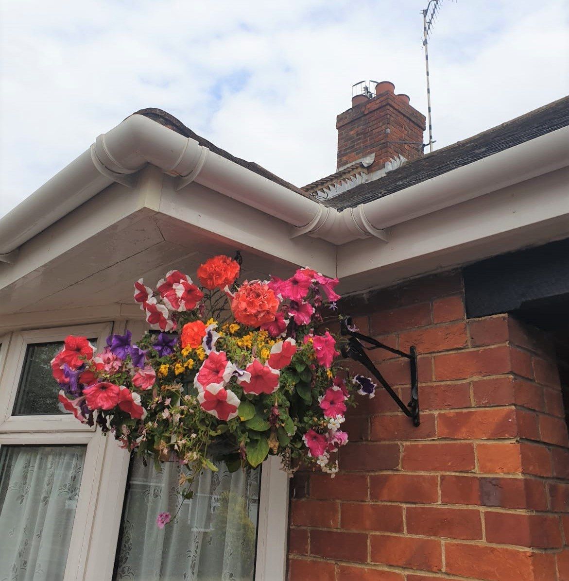 Hanging basket of colorful flowers on a brick house corner under the roofline