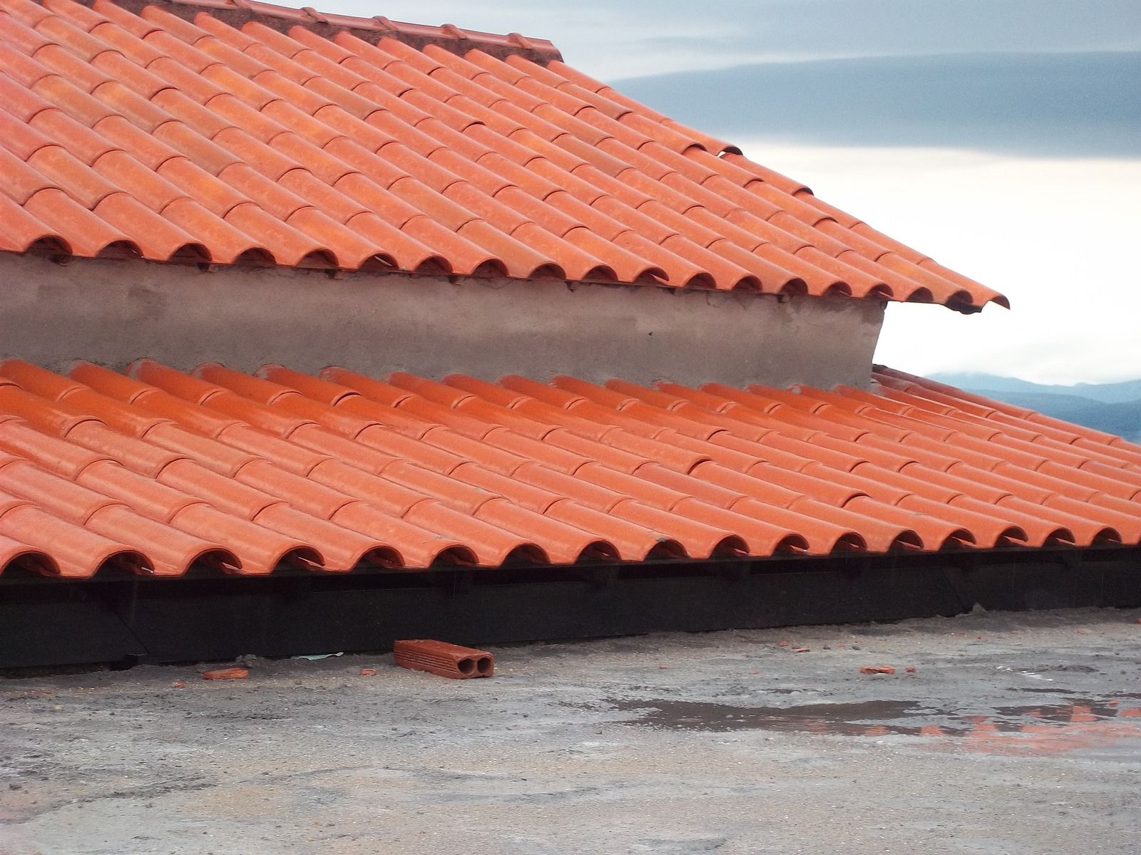 Red tiled roofs on a building against a cloudy sky
