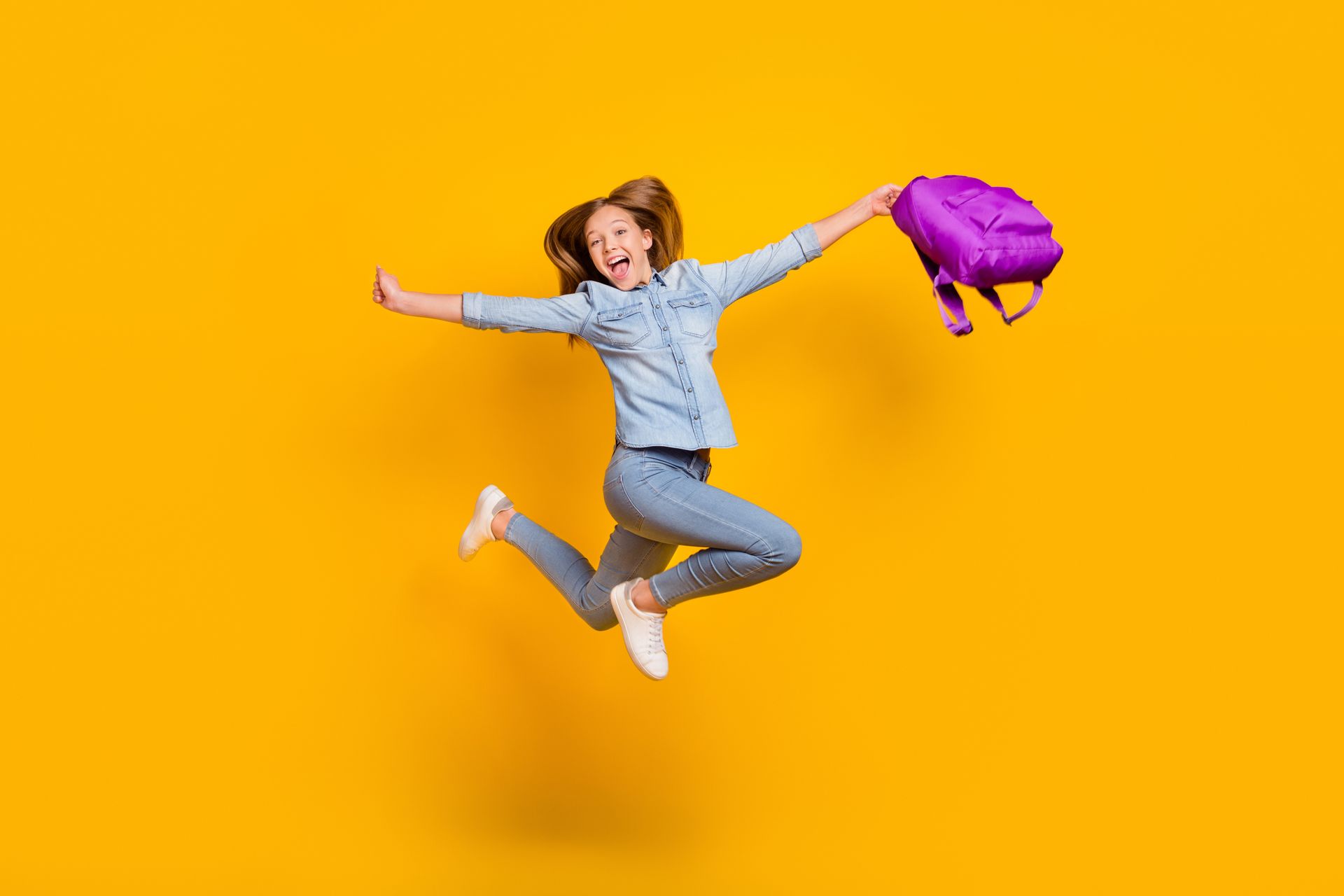 Jeune fille souriante sautant sur un fond jaune