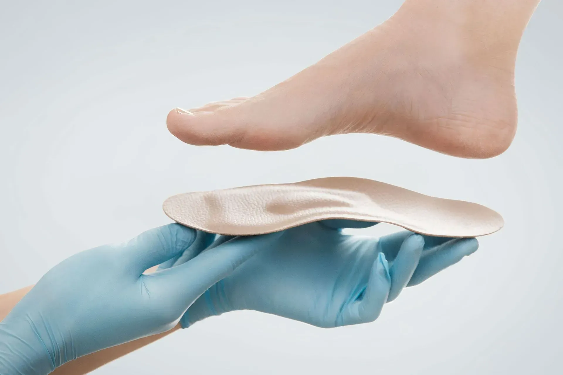 Femme déposant son pied sur une semelle tenue par un professionnel de santé