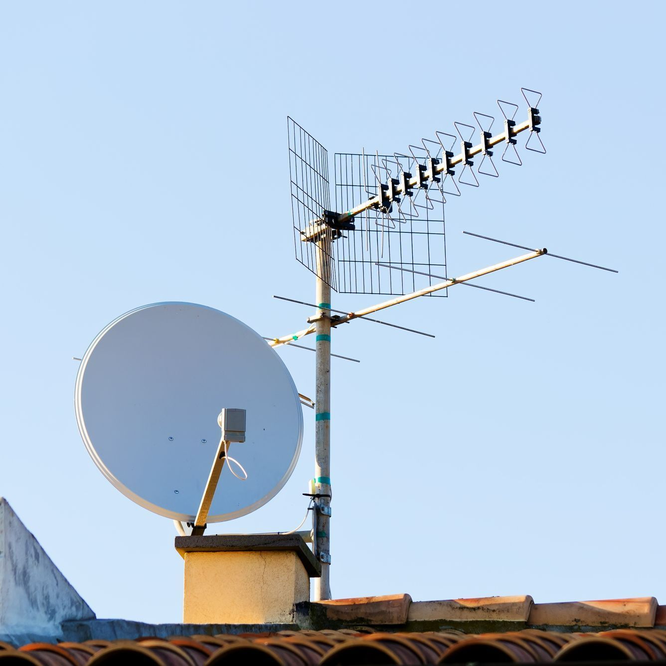 Une antenne parabolique et une antenne rateau sur un toit