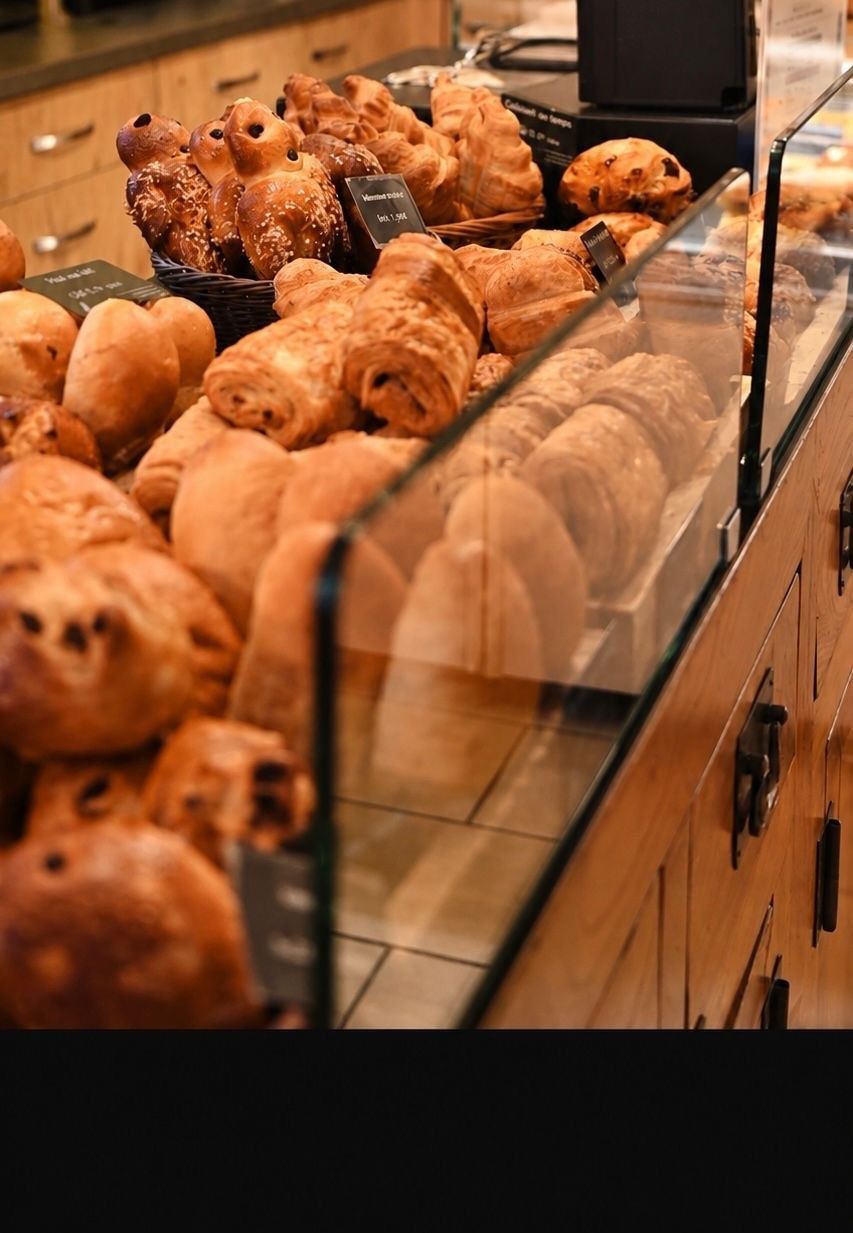 Assortiment de viennoiseries et de petits pains présentés dans une vitrine de boulangerie