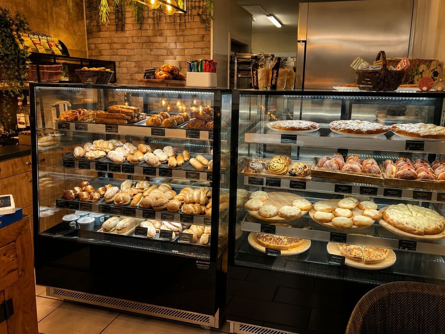 Vitrines de boulangerie remplies de pâtisseries et de tartes assorties dans une boutique chaleureuse et faiblement éclairée