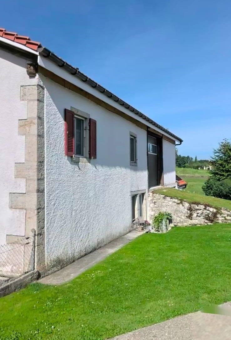 Une maison blanche avec des volets rouges aux fenêtres | Giovannini Plâtrerie-Peinture Sàrl