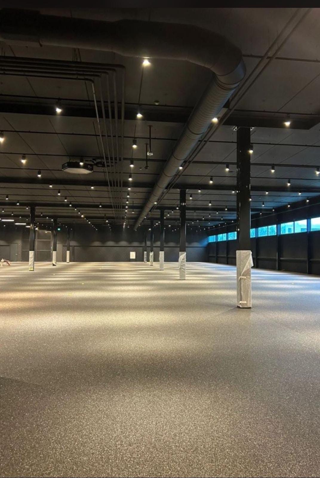 Un grand entrepôt vide avec beaucoup de lumières au plafond | Giovannini Plâtrerie-Peinture Sàrl