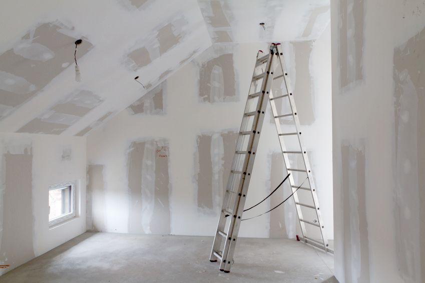 Une pièce vide avec une échelle appuyée contre le mur | Giovannini Plâtrerie-Peinture Sàrl