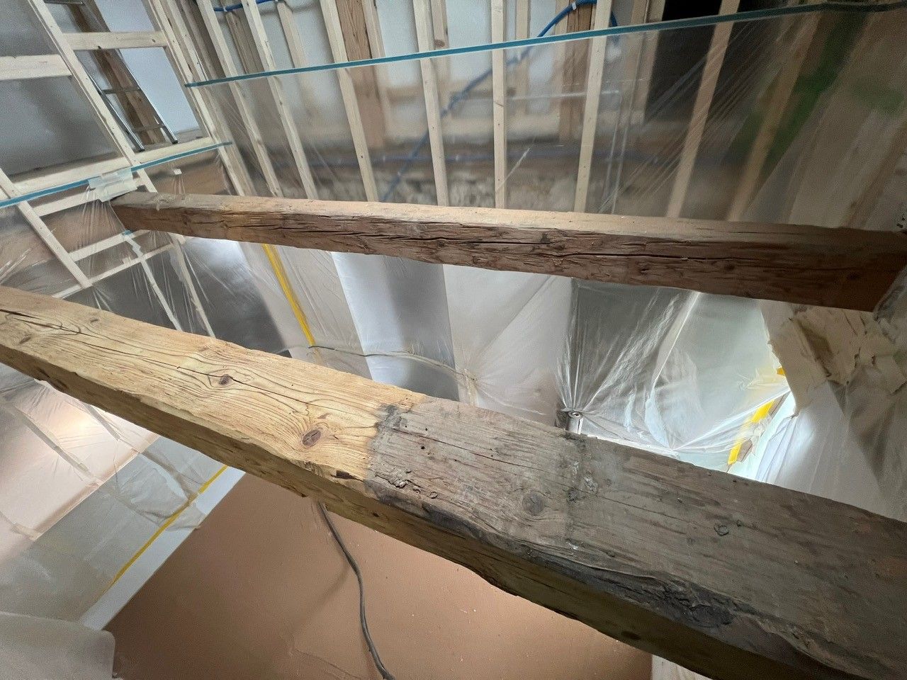 Une poutre en bois est suspendue au plafond d'un bâtiment en construction | Giovannini Plâtrerie-Peinture Sàrl