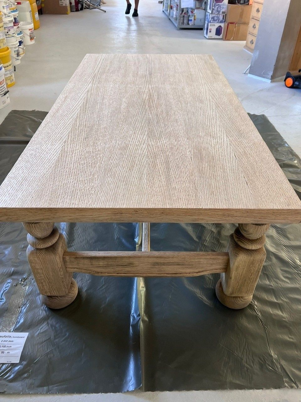 Une table en bois est posée sur un tapis en plastique dans une pièce | Giovannini Plâtrerie-Peinture Sàrl