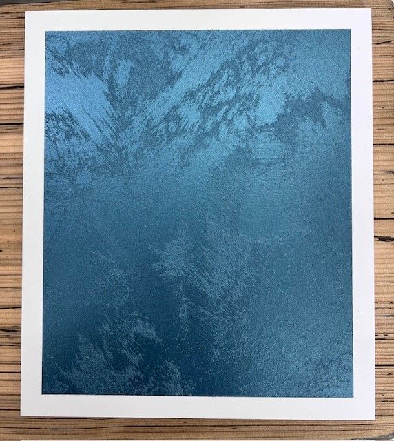 Un morceau de papier carré avec un fond bleu est posé sur une table en bois | Giovannini Plâtrerie-Peinture Sàrl