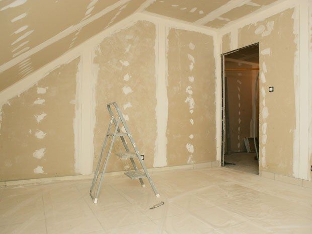 Une pièce vide avec une échelle au milieu | Giovannini Plâtrerie-Peinture Sàrl