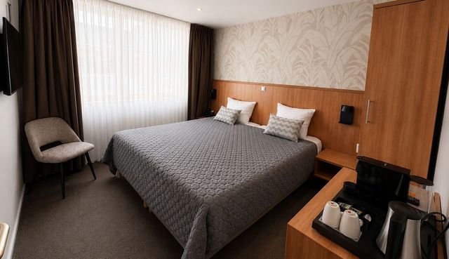 Moderne hotelkamer met een groot bed, stoel, bureau en raam met gordijnen.