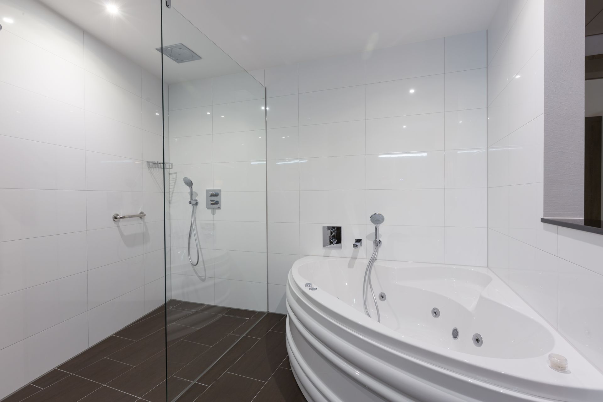 Moderne witte badkamer met glazen douchecabine en groot hoekbad.