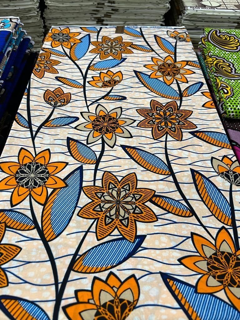 Tissu motif fleur orange et bleu sur fond blanc crème