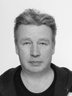 Mustavalkoinen kasvokuva lyhyttukkaisesta miehestä, joka katsoo suoraan eteenpäin neutraalilla ilmeellä.