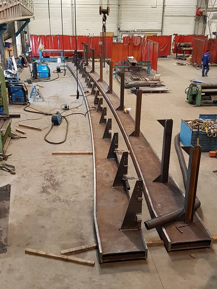 Structure en acier dans un atelier, soutenue par des contreventements angulaires. Une grue est suspendue au plafond.