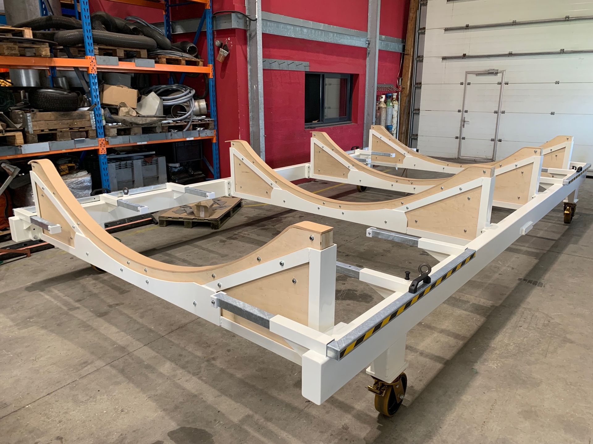 Chariot blanc avec supports en bois courbés, dans un décor industriel.