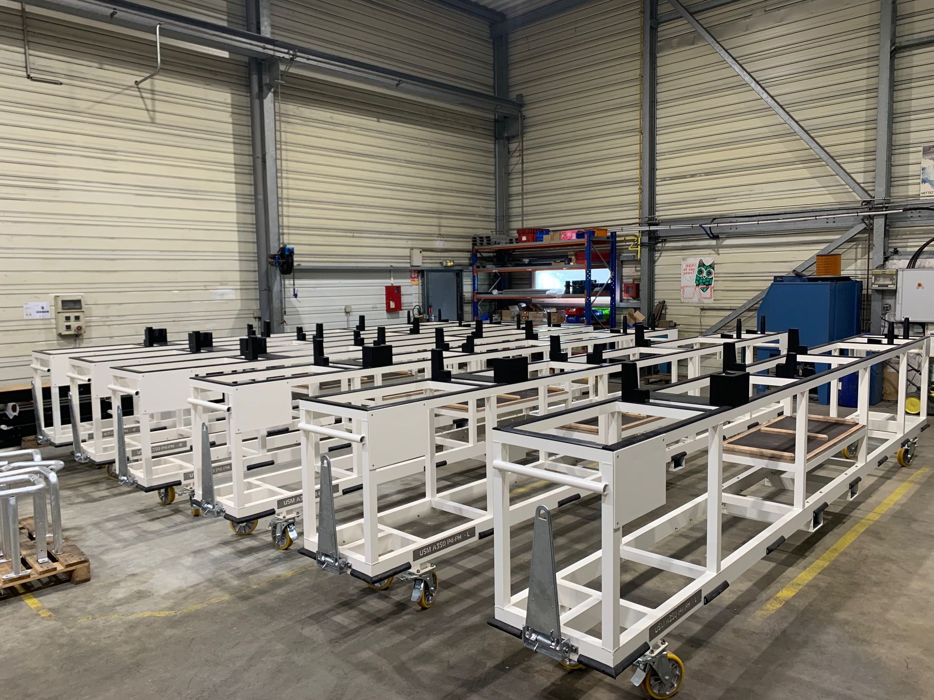 Ligne d'assemblage de cadres en métal blanc sur roues à l'intérieur d'une usine.