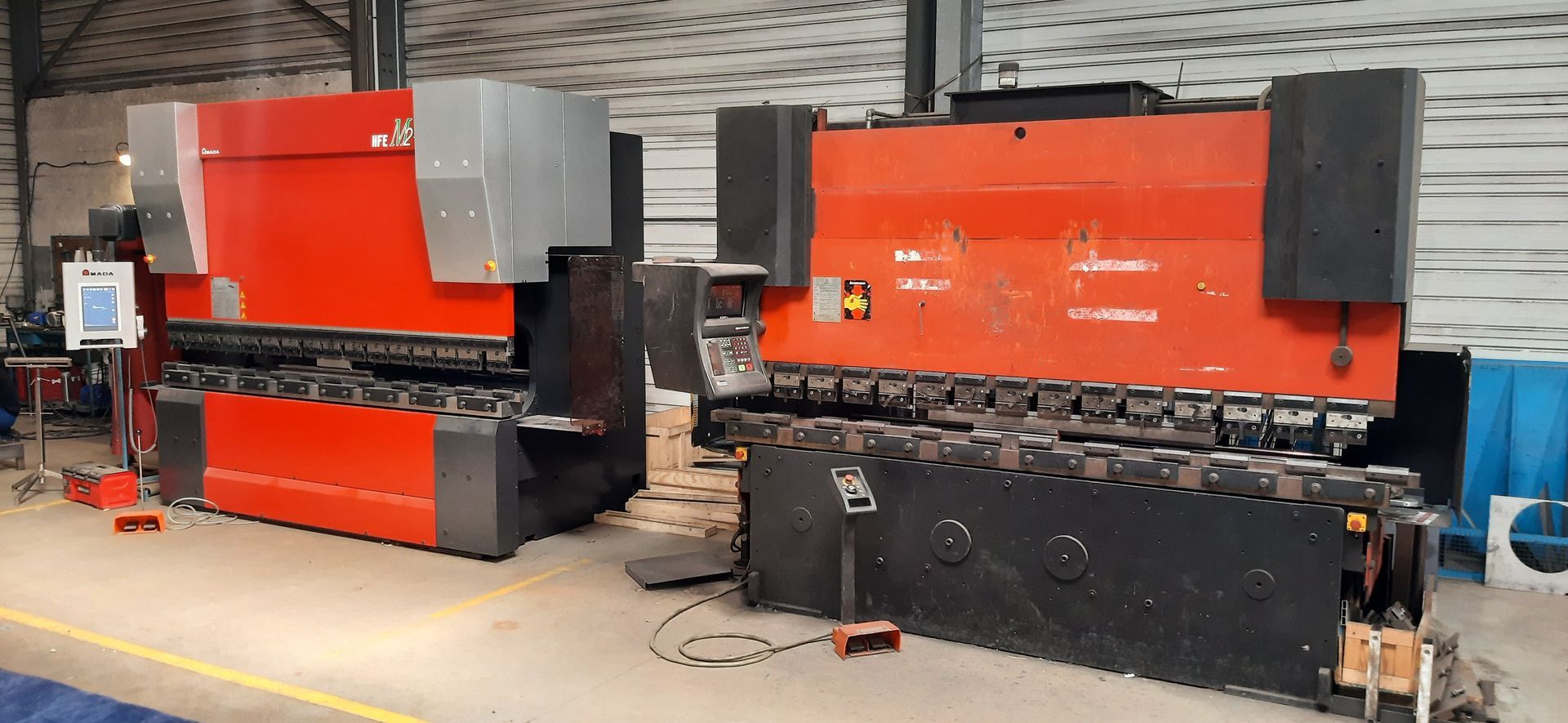 Deux grandes machines industrielles rouges et noires côte à côte dans un atelier.