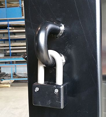 Poteau en métal noir avec une manille, une chaîne et un cadenas attachés pour plus de sécurité.